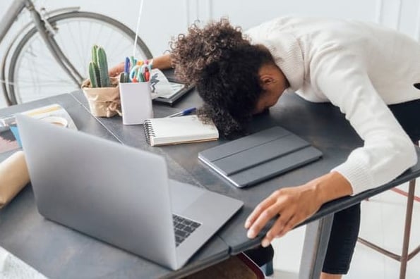 A woman slumps over her desk as she deals with burnout.